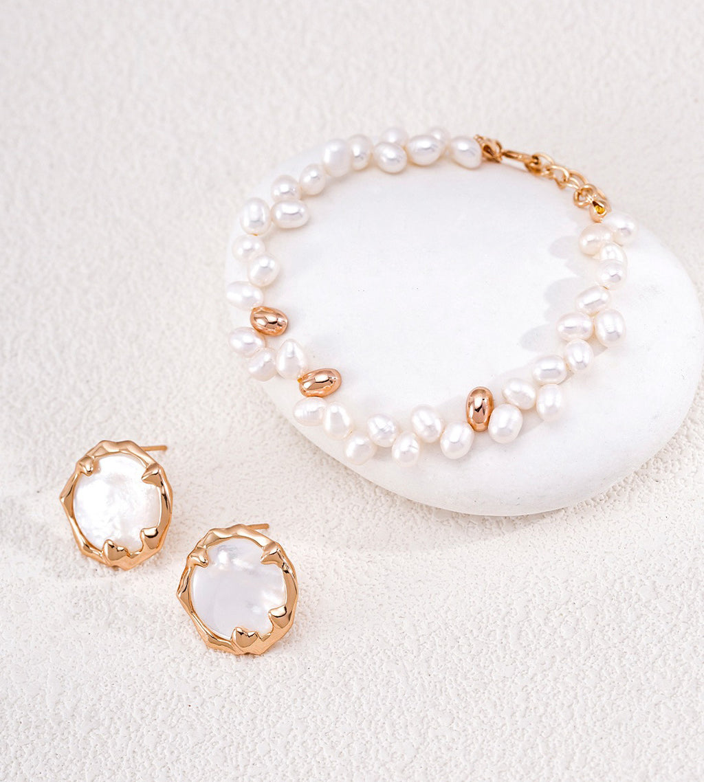 A jewelry set featuring a baroque pearl bracelet and matching stud earrings with gold-toned bezel settings