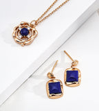 A gold jewelry set featuring a pendant necklace and matching drop earrings, both adorned with deep blue square and round lapis lazuli | BUCKLE Collective