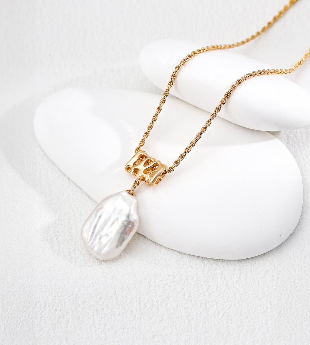 Close-up of an 18K gold-plated S925 silver rope chain necklace with a hollow sculptural connector and lustrous baroque freshwater pearl pendant.