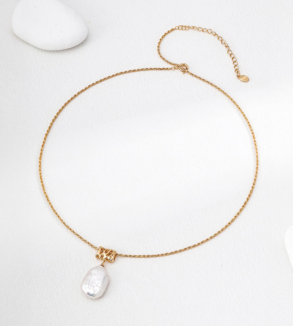 Baroque freshwater pearl pendant necklace laid flat, showing its gold-tone twisted rope chain, lobster clasp and extender