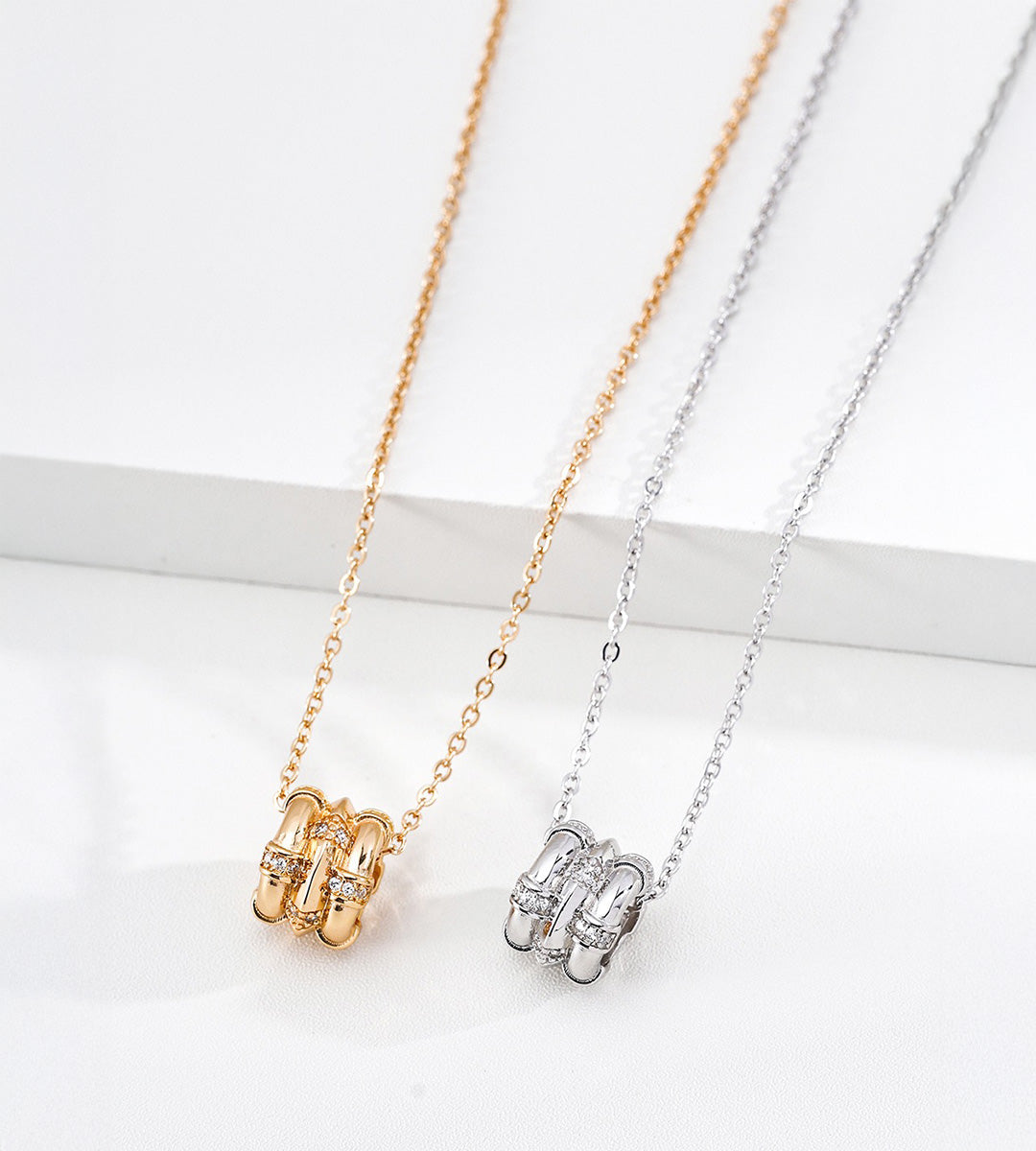 Close-up of bamboo-barrel cubic zirconia pendants in Vintage Gold and White Gold finishes, displayed side by side.