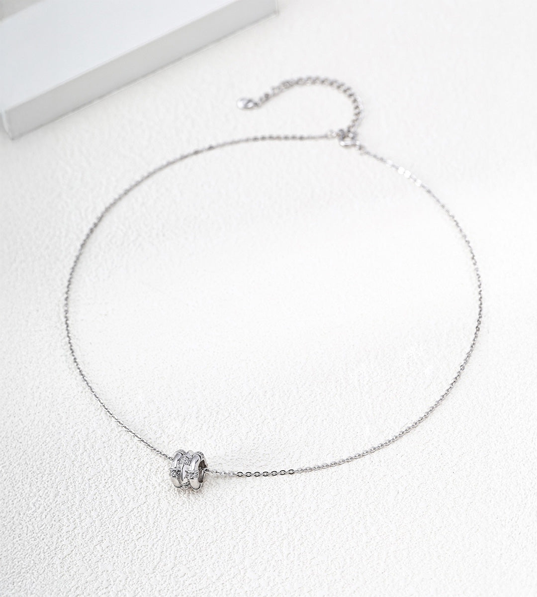 White Gold-finish bamboo-barrel cubic zirconia necklace with a fine chain and extender on a white surface.