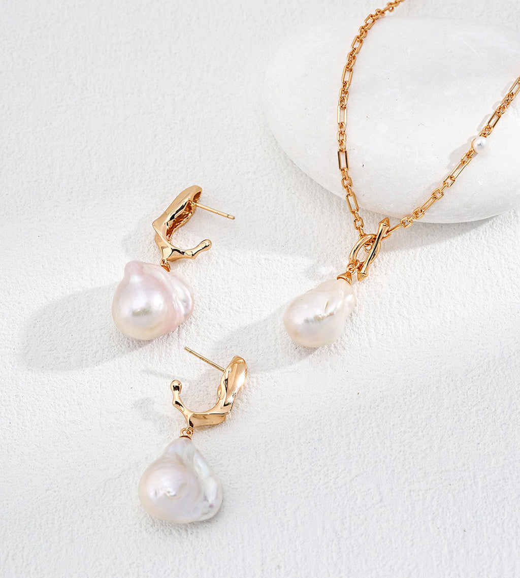 Vintage Gold baroque pearl drop earrings displayed beside a gold-tone chain necklace with a pearl pendant.