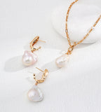Vintage Gold baroque pearl drop earrings displayed beside a gold-tone chain necklace with a pearl pendant.