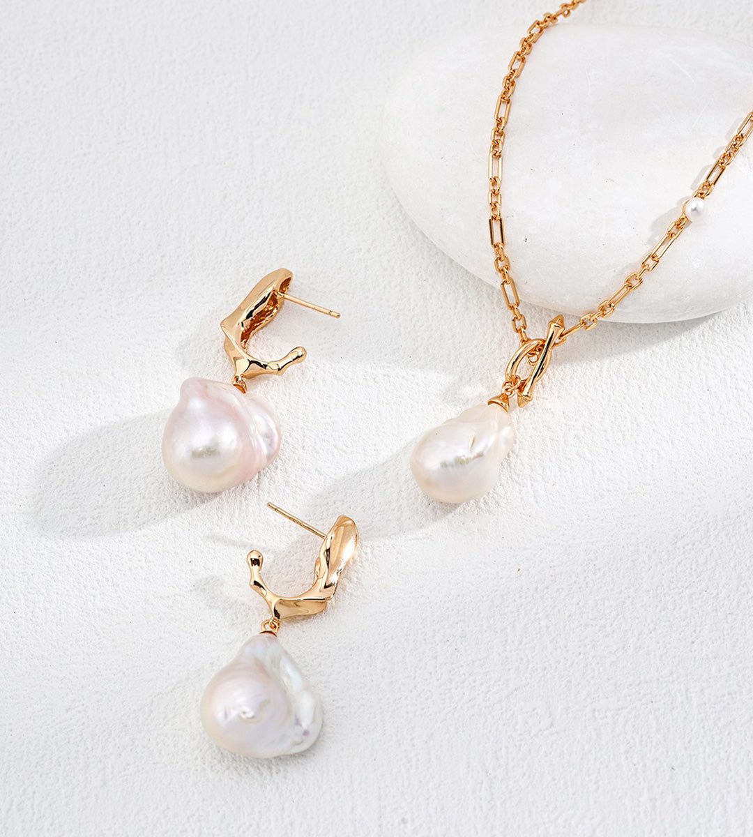 Vintage Gold baroque pearl drop earrings displayed beside a gold-tone chain necklace with a pearl pendant.