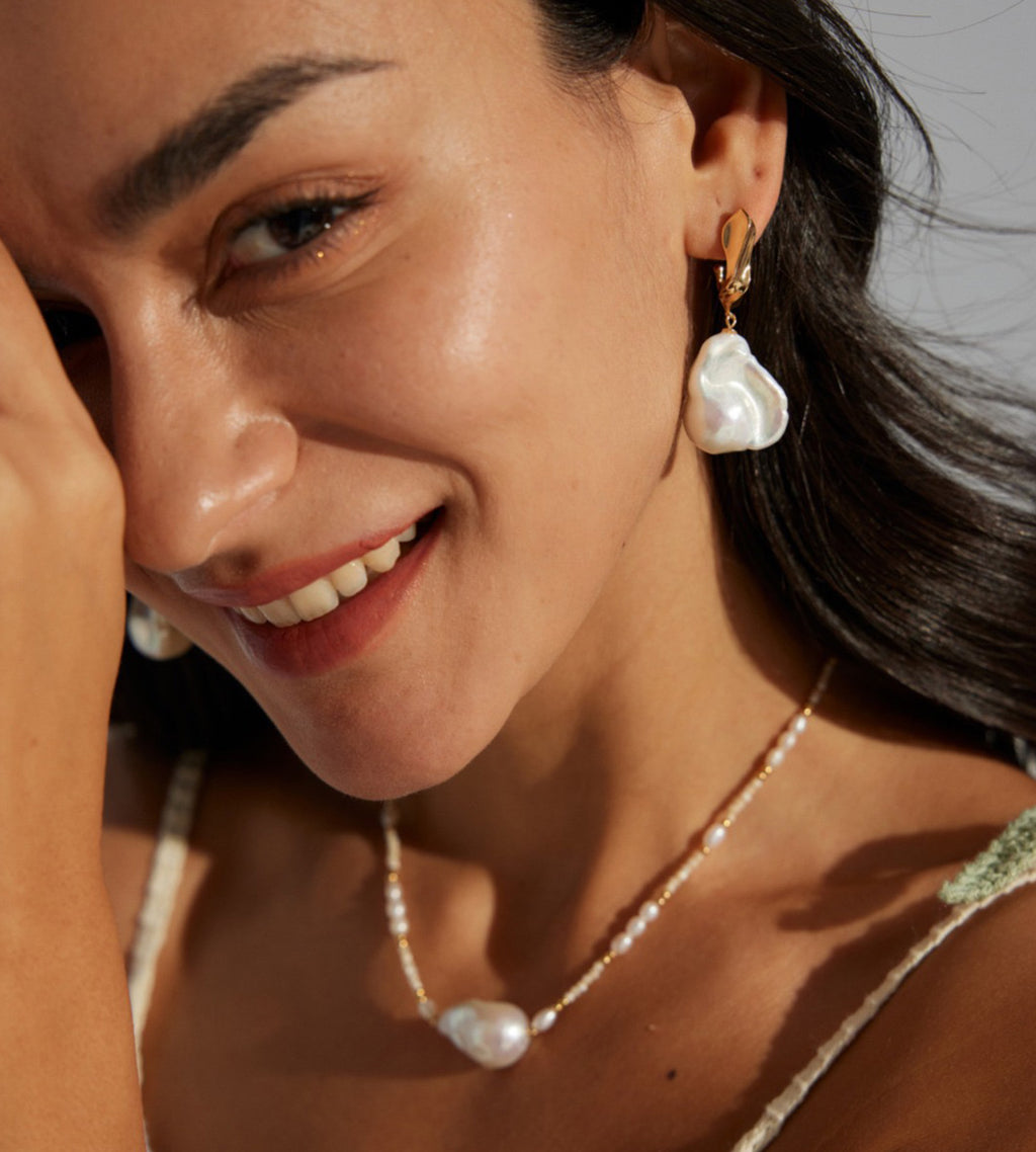 Model wearing Vintage Gold baroque pearl drop earrings styled with a pearl necklace.