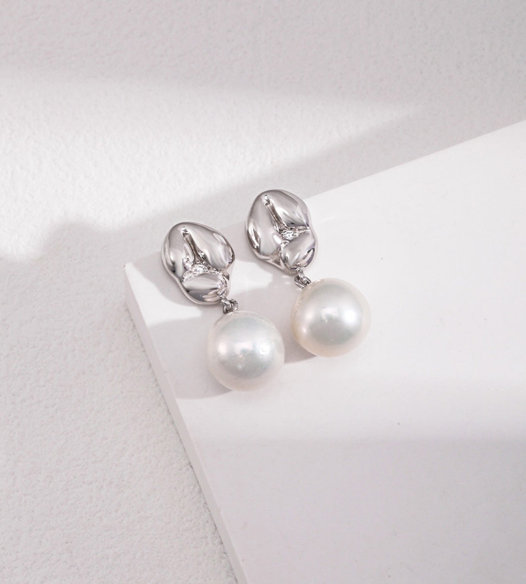 A pair of 18K white-gold-plated S925 silver drop earrings with a polished gold dumpling-shaped top accented with cirzonia and a dangling baroque white pearl