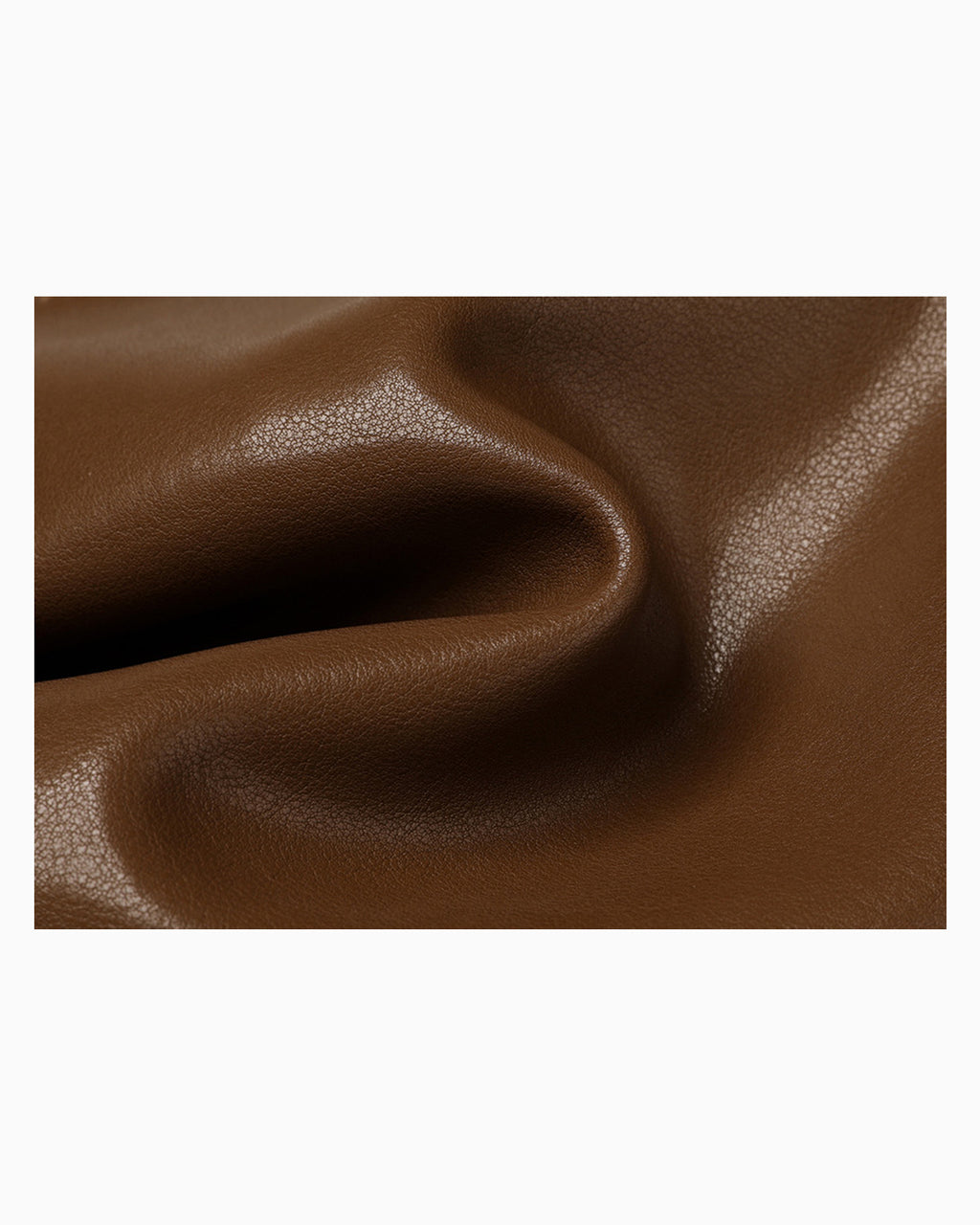 A close-up of brown leather with a glossy, pebbled texture