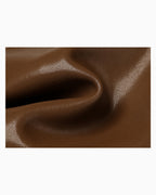 A close-up of brown leather with a glossy, pebbled texture