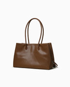 A medium brown leather tote bag with double top handles