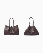 Two dark brown woven leather large tote bags with double top handles and a drawstring detail, displayed side by side, showing the folding style