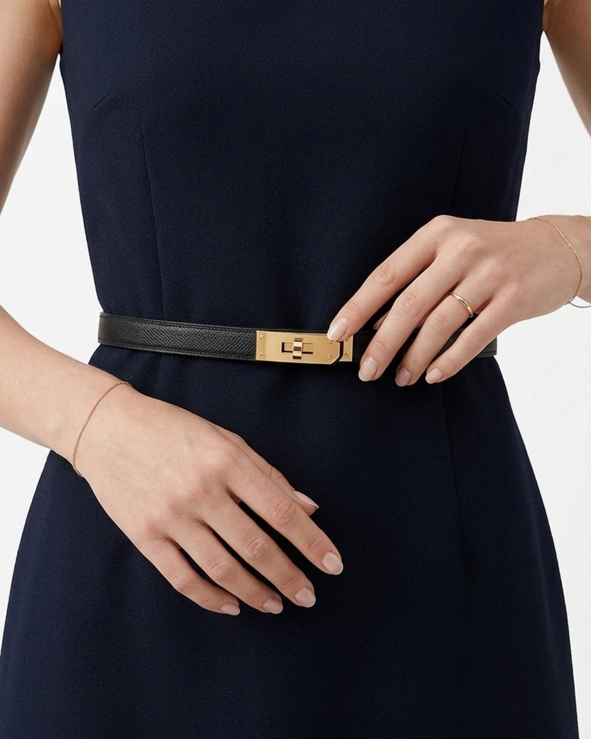 A close-up of a model wearing a slim Black Classic Saffiano Leather Belt with Gold Turn-Lock Buckle, paired with a dark navy dress.
