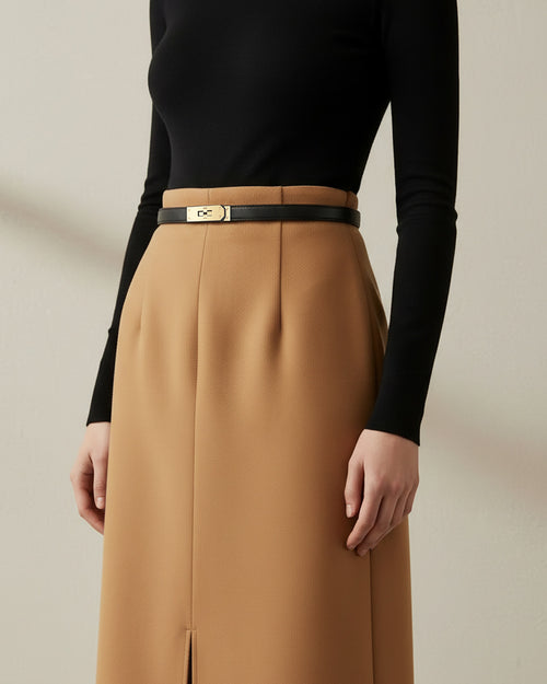 A model wearing a black long-sleeve top and a high-waisted camel brown skirt with a thin Black Classic Saffiano Leather Belt with a gold turn-lock buckle