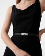 A model wearing a sleeveless black dress with a thin black saffiano leather belt with a silver-tone turn-lock buckle