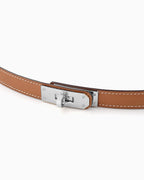 A close-up of a saffiano leather belt in caramel color with a silver-toned turn-lock buckle and contrast stitching