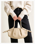 Woman in a stylish casual outfit with a beige pleated dumpling leather handbag with a knotted strap