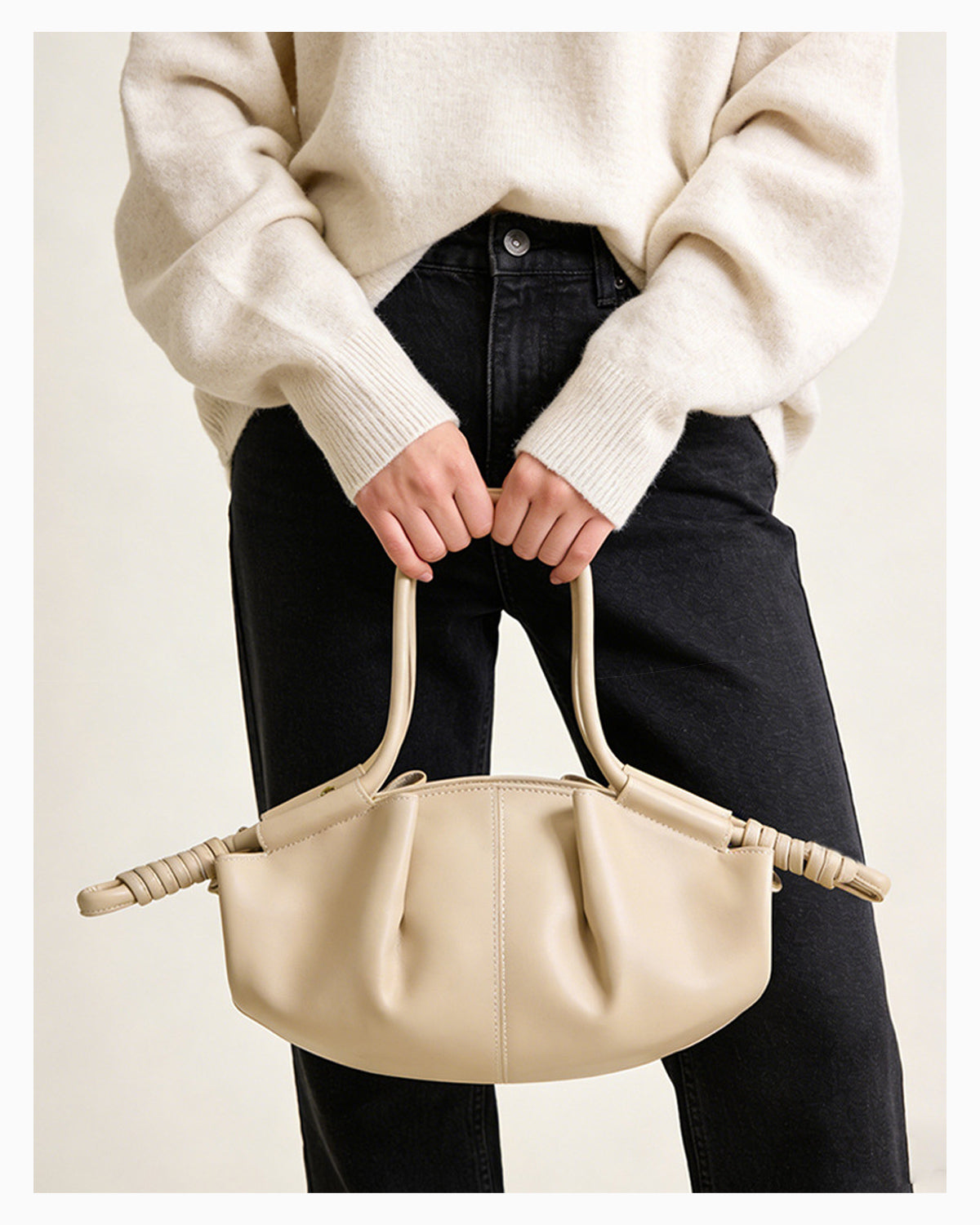 Woman in a stylish casual outfit with a beige pleated dumpling leather handbag with a knotted strap