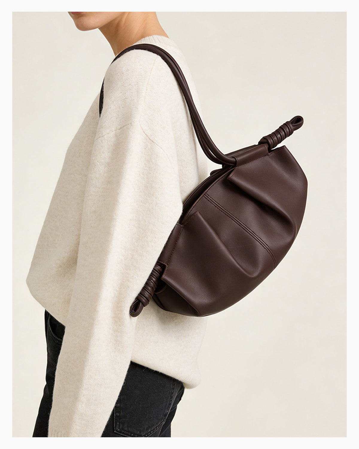 Woman in a stylish casual outfit with a brown pleated dumpling leather handbag with a knotted strap