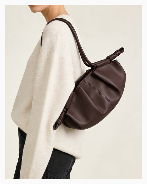 Woman in a stylish casual outfit with a brown pleated dumpling leather handbag with a knotted strap