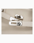 Close-up of an off-white pebbled Togo leather handbag with silver-toned turn-lock closure