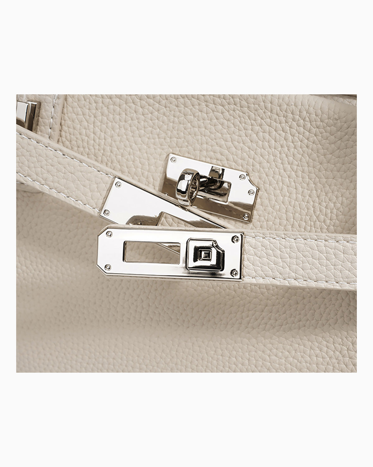 Close-up of an off-white pebbled Togo leather handbag with silver-toned turn-lock closure