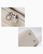 Close-up detail shots of an off-white pebbled Togo leather bag, showing a silver-tone zipper with decorative metal pulls and two silver rivets on the bag's bottom.