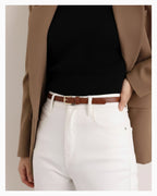A woman in a smart-casual outfit wearing a 2‑in‑1 transformable classic leather belt with a gold buckle. The belt transforms from a statement, wide design into a slim classic design, Caramel Color