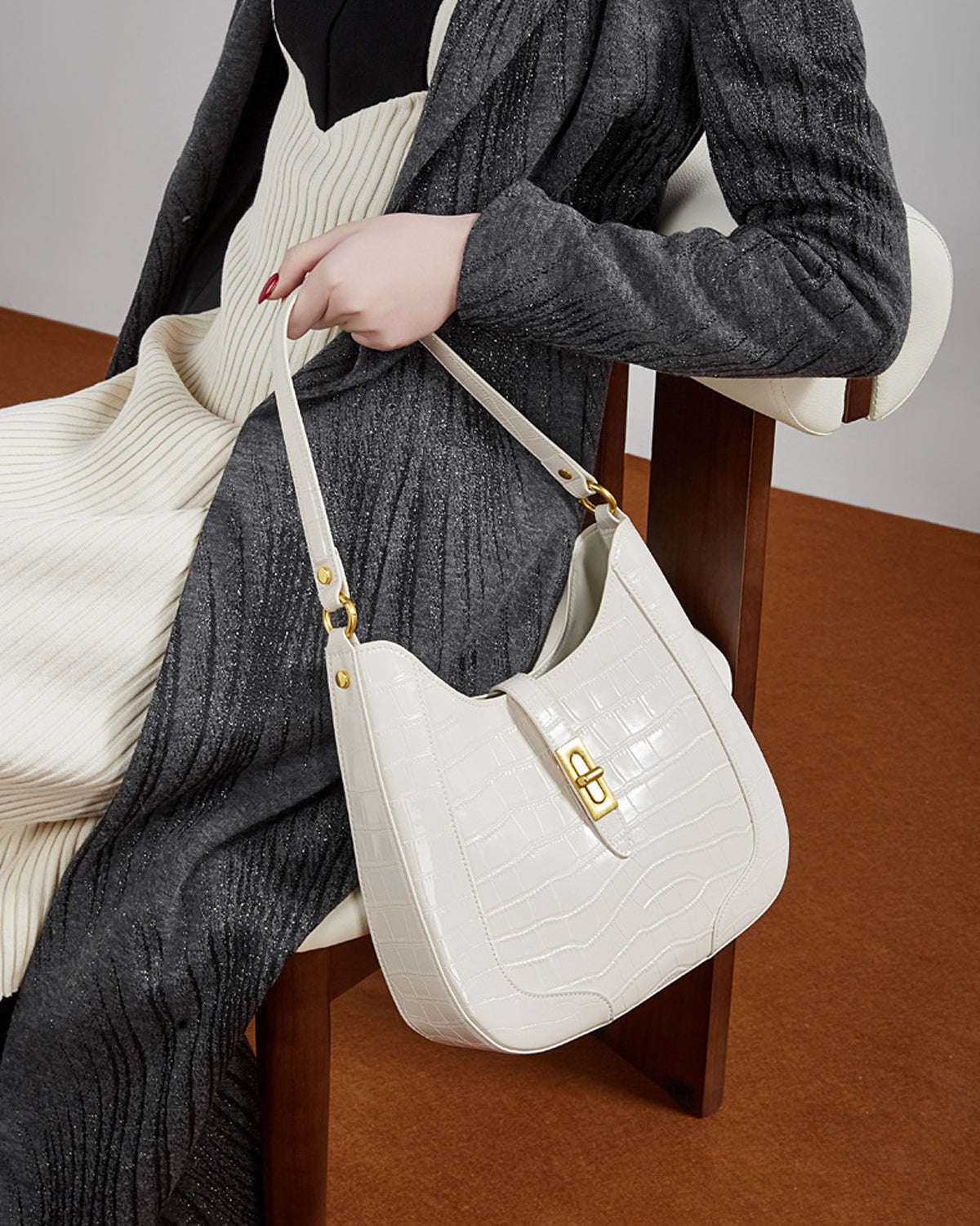 Woman sitting on a chair with an Elegant Crocodile-Pattern White Genuine Leather Shoulder Bag with Gold Hardware