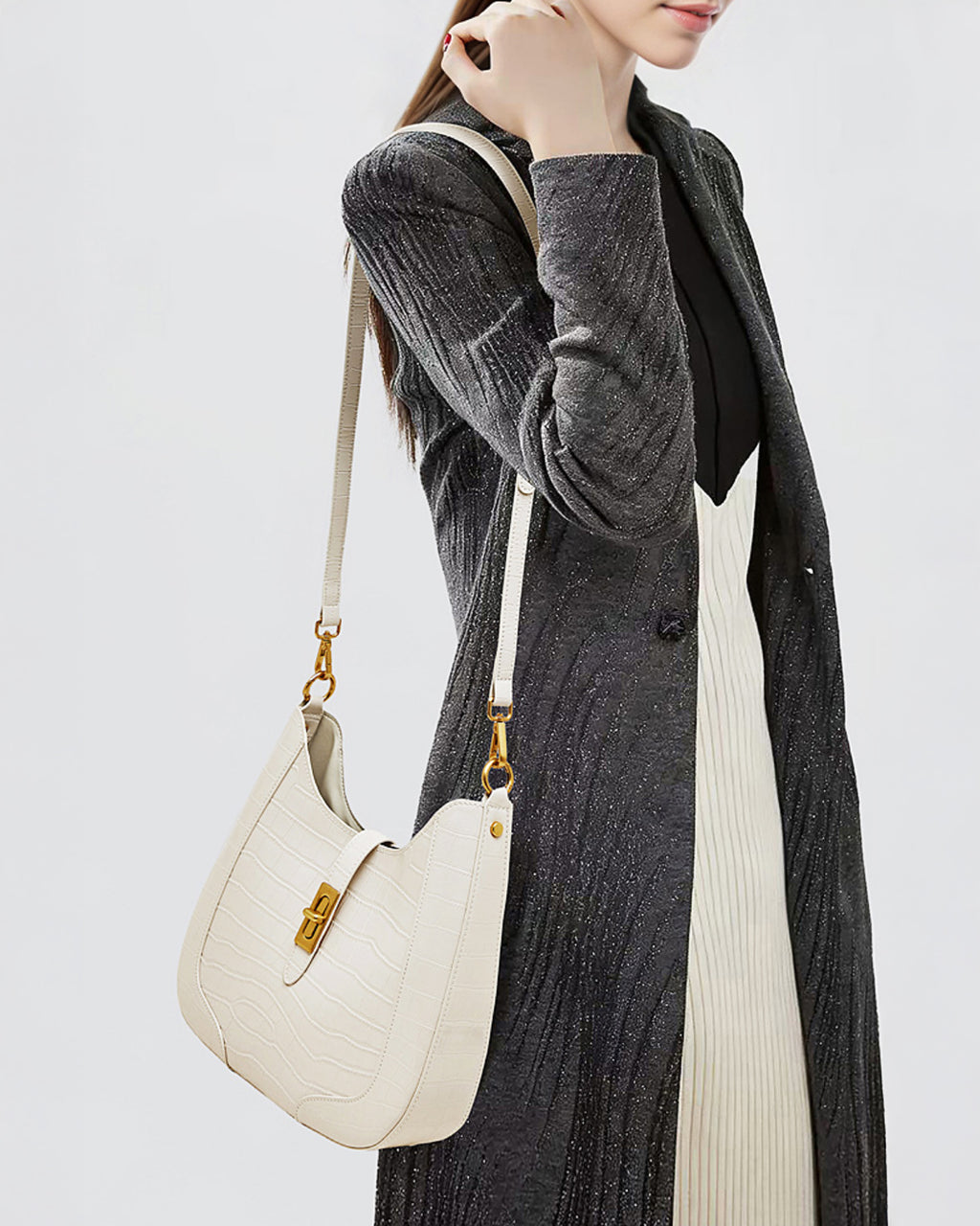 Woman in an elegant outfit with a crocodile-pattern white genuine leather shoulder bag with gold hardware and a crossbody strap