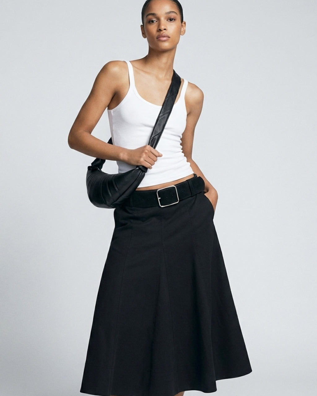 Stylish woman in a fashionable black and white outfit wearing a Black Leather Crescent Croissant Shoulder Crossbody Bag