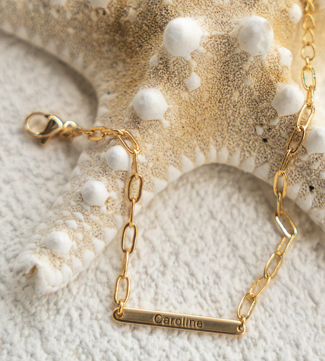 "Your Name" Custom Letter Bracelet with the name Caroline on it, lying next to the sea star, 925 Sterling Silver, 18K Gold-plated