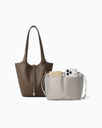 Extra Large Togo Leather Bucket Tote Bag in Elephant Grey Color with Gold-toned Lock shown next to a removable light gray drawstring pouch