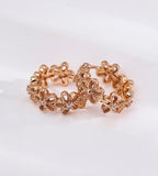 Floral hollow-carved huggie hoop earrings in 18K vintage gold plating — continuous CZ flower band, openwork floral silhouette, S925 sterling silver, BUCKLE Collective