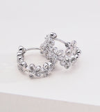Floral hollow-carved huggie hoop earrings in 18K white gold plating — continuous CZ flower band, openwork floral silhouette, S925 sterling silver, BUCKLE Collective
