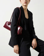 Stylish woman in a polished black outfit wearing a Leather Baguette Handbag in Wine Red Color