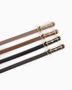 Four leather belts in khaki, caramel, black, and coffee-brown, each with a gold-tone horsebit buckle, arranged diagonally on a white background.