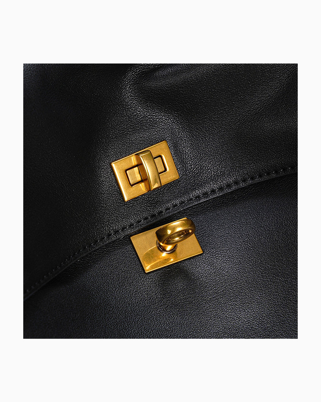 Close-up of a black leather bag with two gold-tone metal lock closures