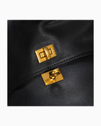 Close-up of a black leather bag with two gold-tone metal lock closures