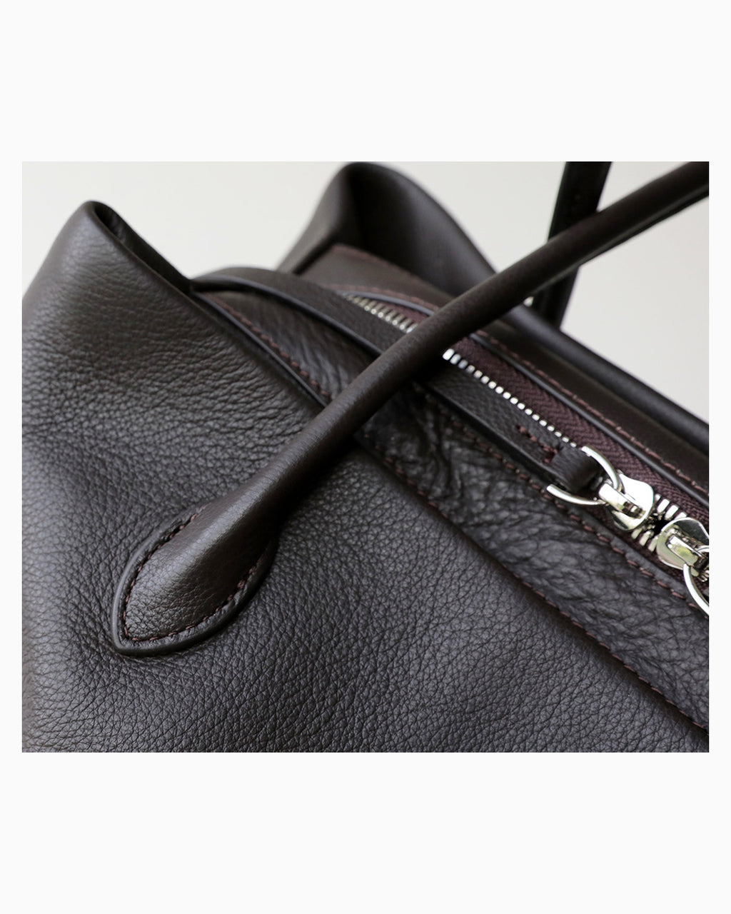 Close-up of a dark brown pebbled leather shoulder bag showing a silver zipper and a leather strap detail | BUCKLE Collective