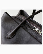 Close-up of a dark brown pebbled leather shoulder bag showing a silver zipper and a leather strap detail | BUCKLE Collective