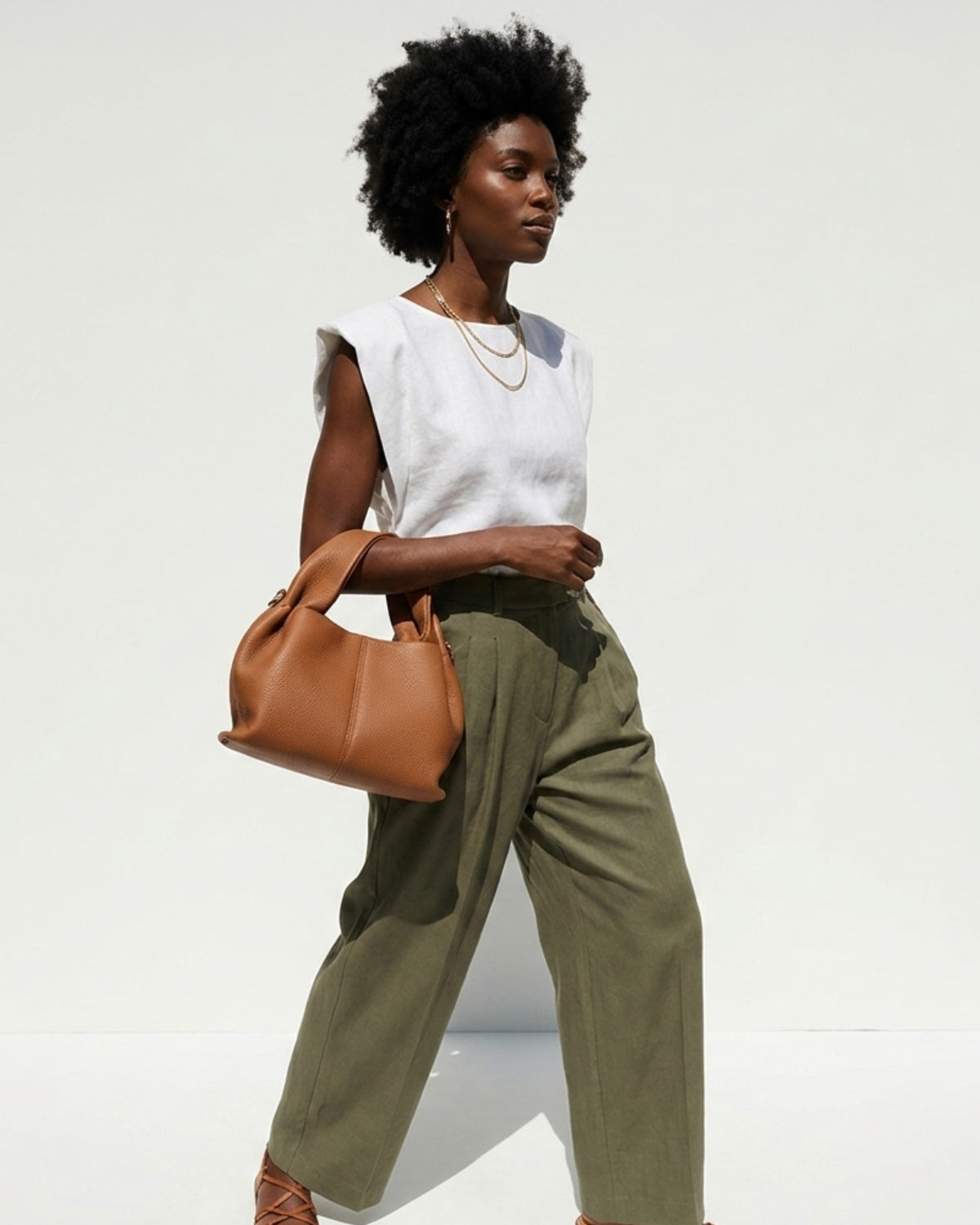 A woman in a stylish casual summer outfit carries a Genuine Leather Cloud-shaped Satchel Handbag, Caramel color