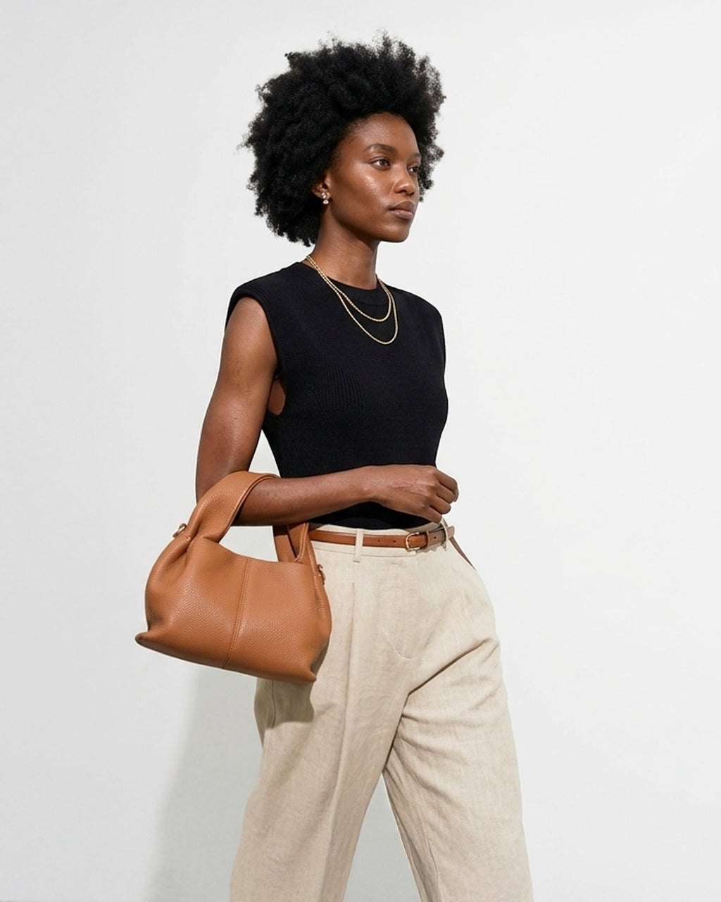 A woman in a stylish smart-casual outfit carries a Genuine Leather Cloud-shaped Satchel Handbag in Caramel color