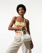 A woman in a stylish, vibrant summer outfit carries a White Genuine Leather Cloud-shaped Satchel Handbag with Detachable Strap
