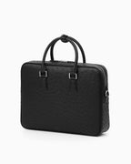 A black genuine ostrich leather briefcase with dual top handles and silver-tone hardware by BUCKLE Collective
