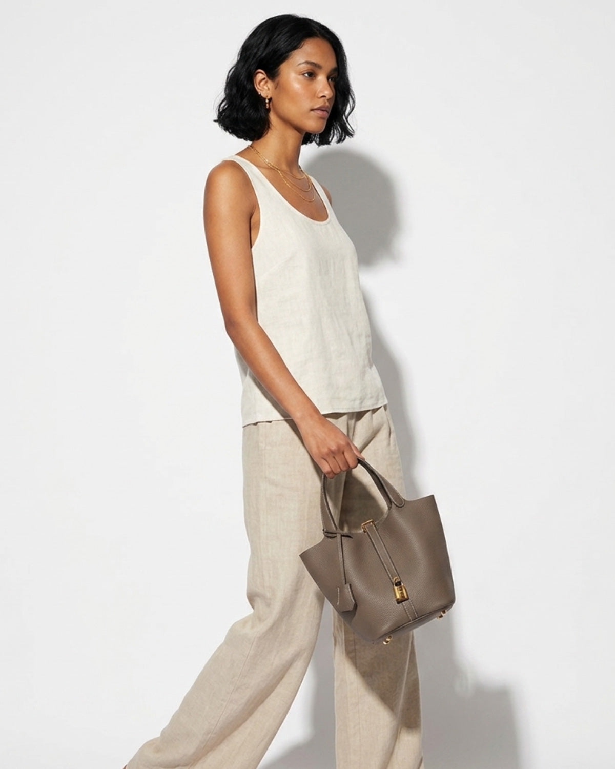 Woman in a stylish summer outfit with a Genuine Togo Leather Bucket Bag in Elephant Grey color with Gold Lock and Key
