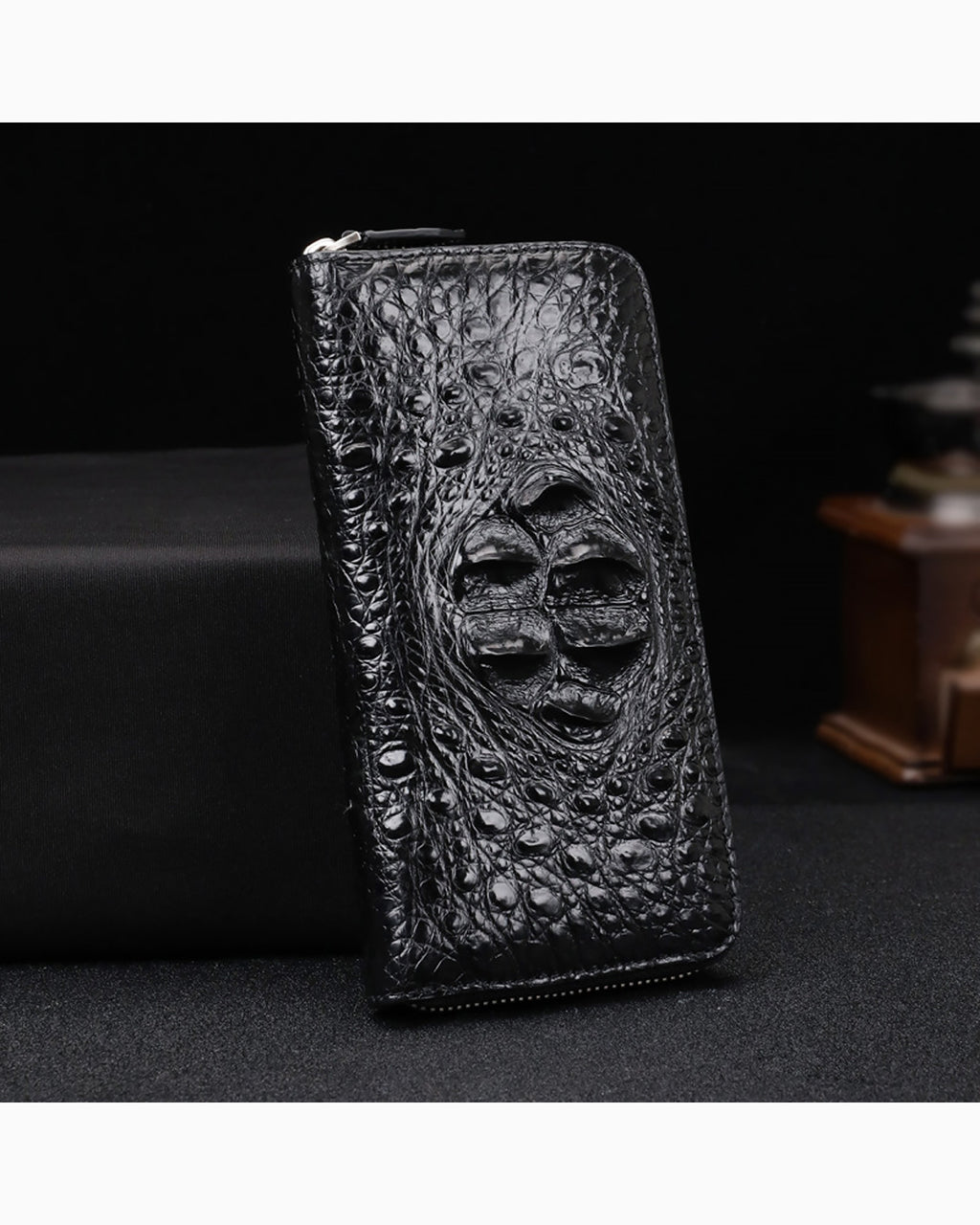 Black Genuine Siamese Crocodile Leather Clutch standing upright on a dark surface against a black background.