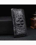 Black Genuine Siamese Crocodile Leather Clutch standing upright on a dark surface against a black background.