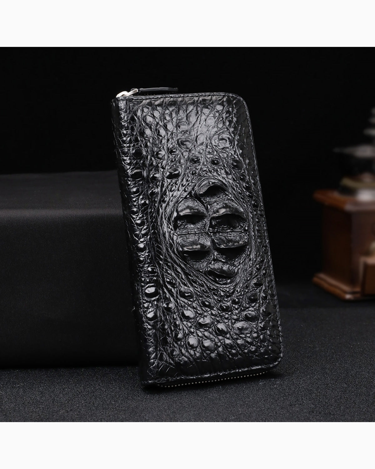Black Genuine Siamese Crocodile Leather Clutch standing upright on a dark surface against a black background.