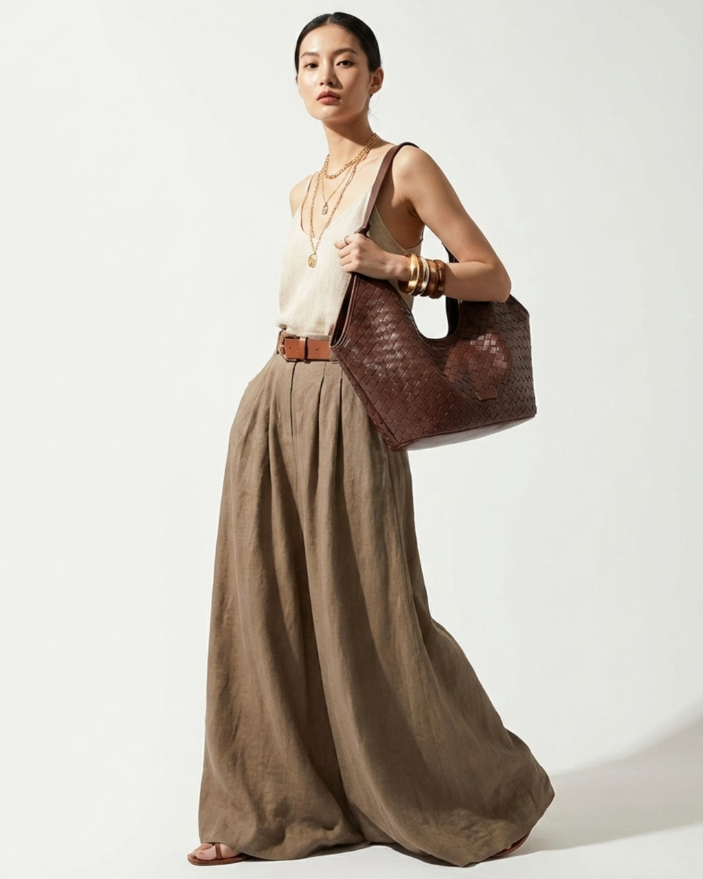 Woman in an elegant and stylish casual summer outfit with a brown woven genuine leather hobo shoulder tote bag