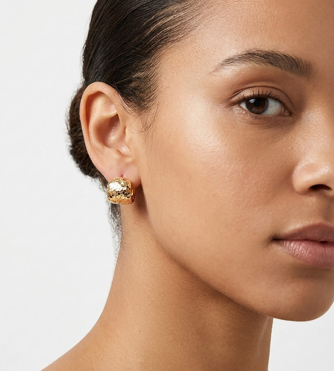 A close-up of a model's ear and side profile wearing Glitter Textured Pillow Huggie Earrings | 18K Gold Plated S925 Silver | BUCKLE Collective